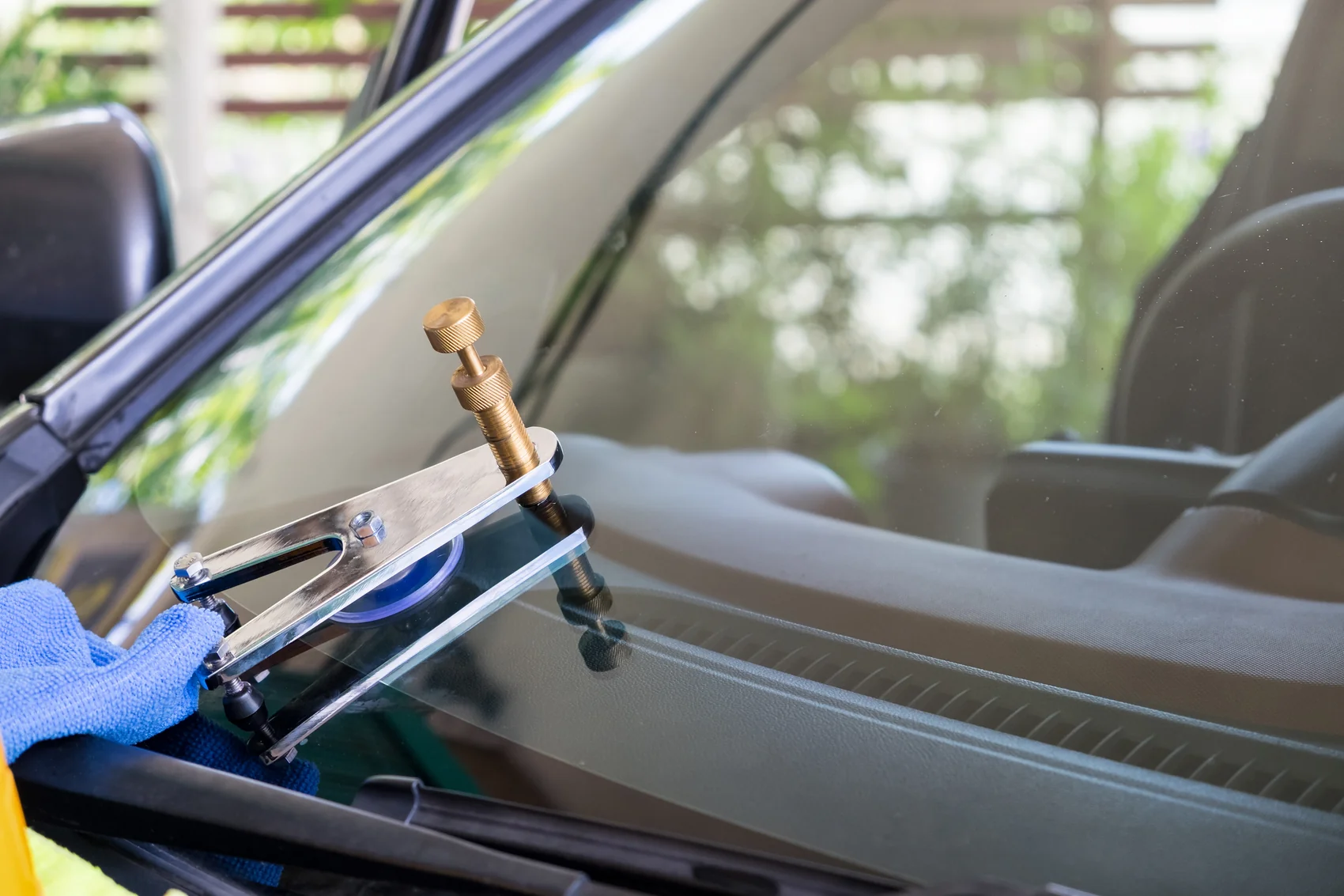 Technician using a bridge tool for windshield repair on a rock chip