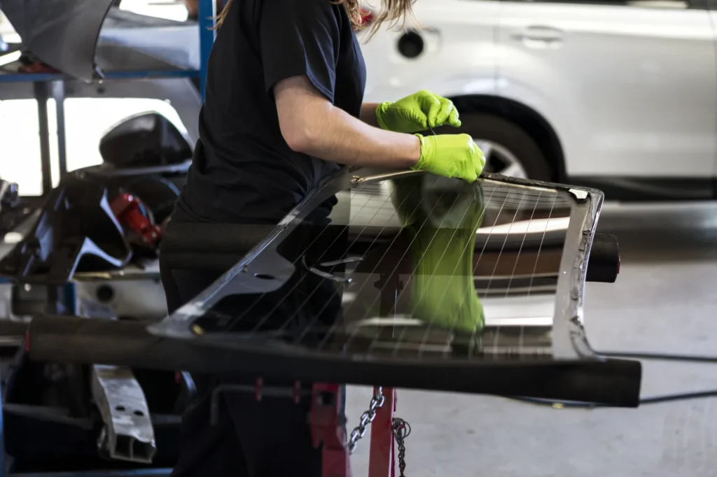 Technician performing commercial auto glass repair on a windshield in the shop