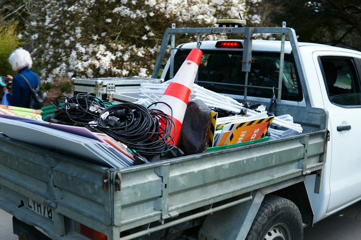 Pickup truck bed loaded with electrical cable, a traffic cone and job-site signs