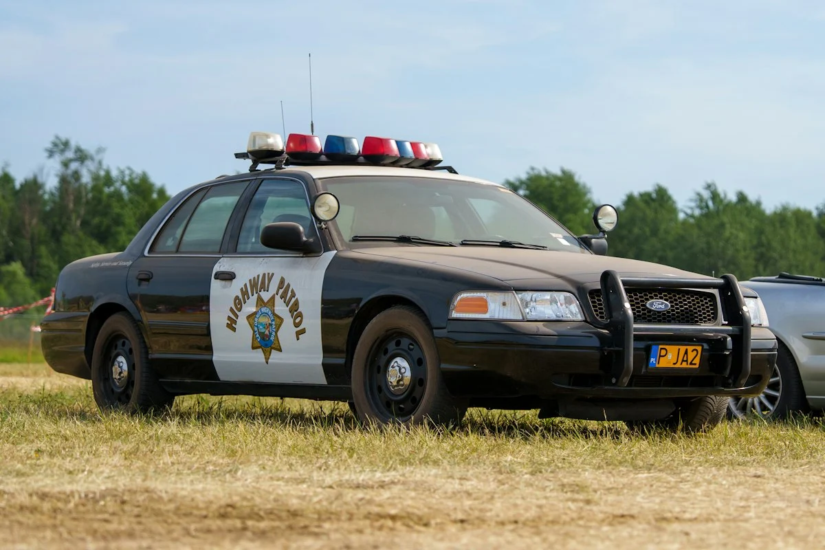 Black and white highway patrol car parked on grass