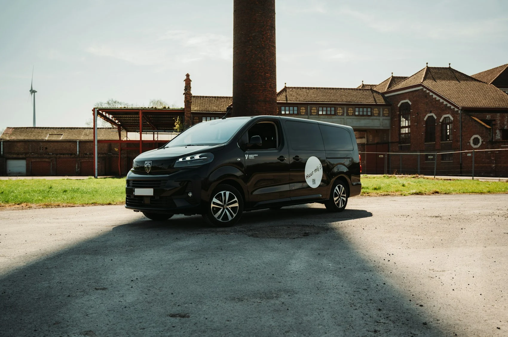 Black work van parked in front of an industrial building